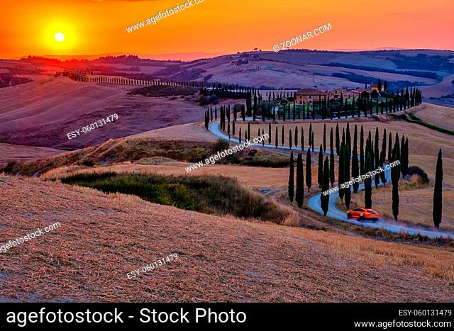 Tuscany, Crete Senesi rural sunset landscape. Countryside farm, cypresses trees, greenfield, sunlight and cloud. Italy, Europe