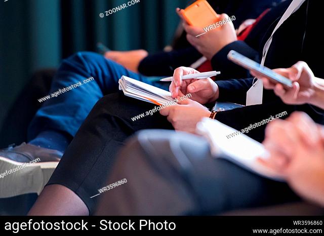closeup shot of business people hands using pen while taking notes on education training during business seminar at modern conference room