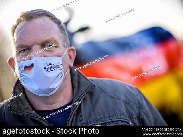 19 November 2020, Mecklenburg-Western Pomerania, Wismar: A dairy farmer wearing a mouth-and-nose protector with the inscription ""Die faire Milch"" (The fair...