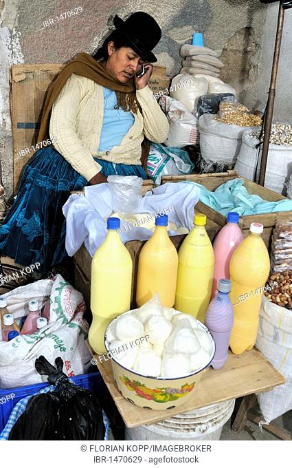 Street sale of fresh cheese and other agricultural products from the Penas Valley, saleswoman on a mobile phone, Oruro, Bolivia, South America