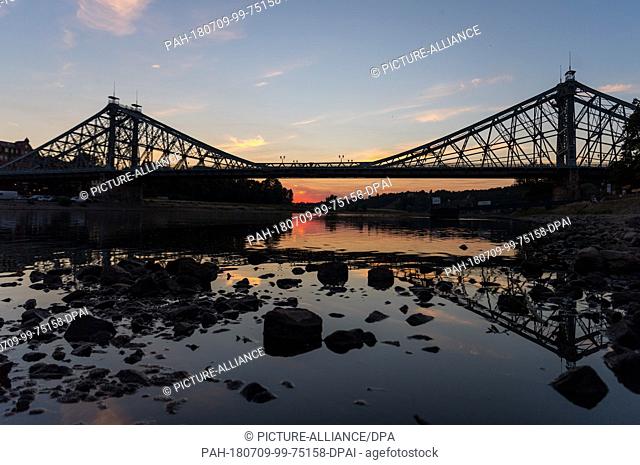 04 July 2018, Germany, Dresden: The setting sun dyes the sky behind the scenery of the bridge 'Blaues Wunder' (lit. blue wonder; Loschwitz Bridge)