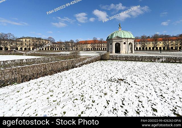 22 March 2020, Bavaria, Munich: On a lawn in front of the temple of Diana in the Hofgarten lies snow. In Bavaria, exit restrictions are in place to curb corona...