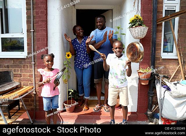 Portrait happy family celebrating with pots and pans on sunny patio