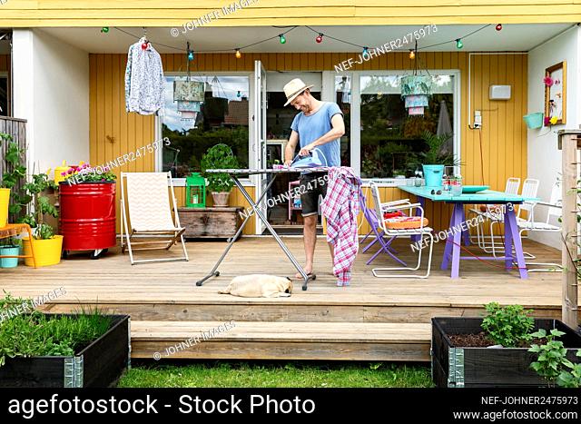 Man ironing clothes on patio