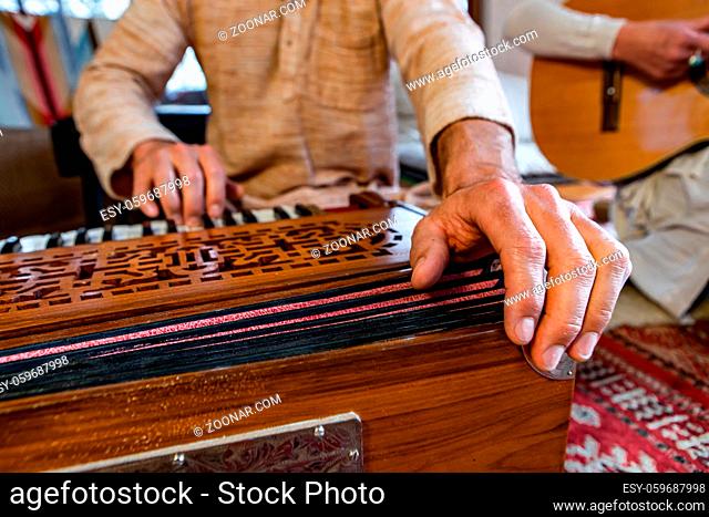 Front angle view of senior male shamanic playing indian musical instrument harmonium as sacred and kirtan music for peaceful yogic power