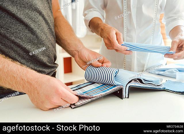 Tailor and customer choosing material for bespoke shirt from pattern book