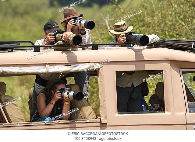 Tourists, photographers taking pictures of wildlife at the Mara river during the great wildebeest migration. Masai Mara National Reserve, Kenya