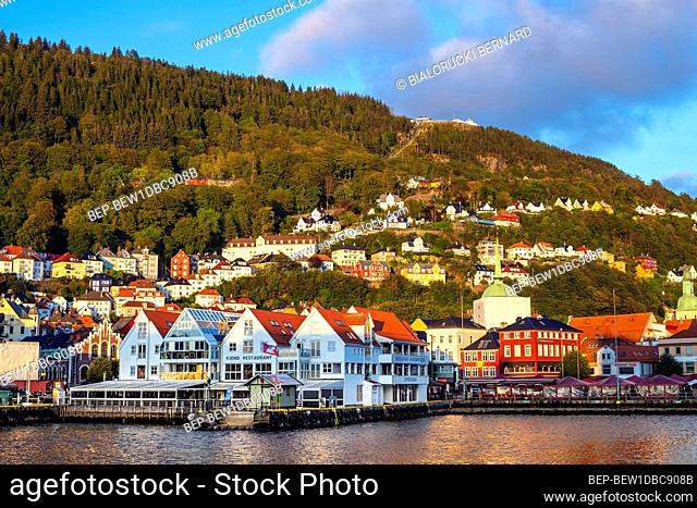Bergen, Hordaland / Norway - 2019/09/03: Panoramic view of historic city center along Bryggen street at the Bergen harbor with Holy Cross church and Floyen...