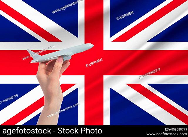 Airplane in hand with national flag of United Kingdom. Travel to United Kingdom