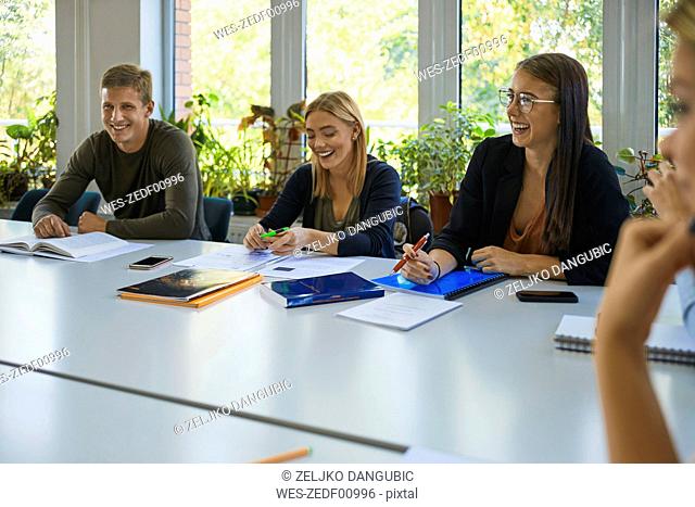 Laughing students sitting at table at university