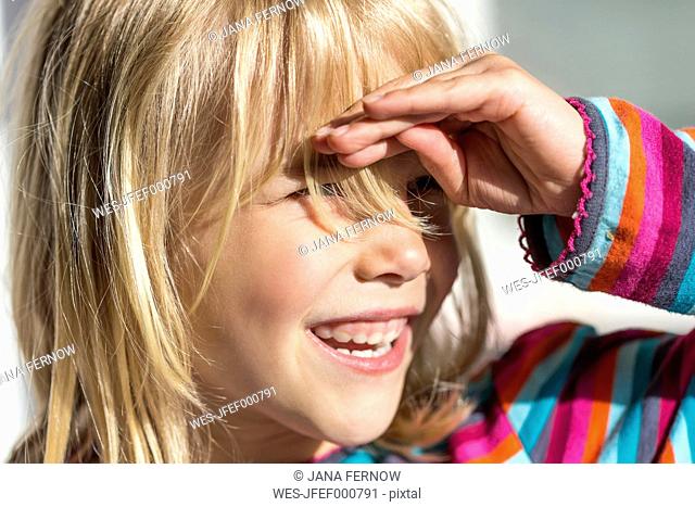 Portrait of little girl shielding her eyes while looking at distance