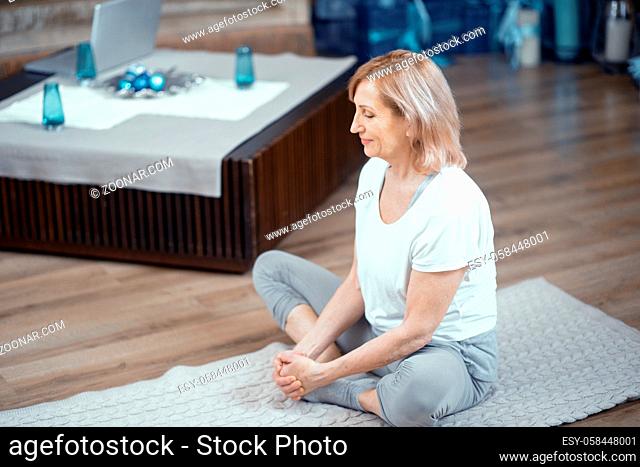 Adult Woman Does Yoga at Home. In Asana Position She Sits on the Floor. After Practicing Yoga She Meditates