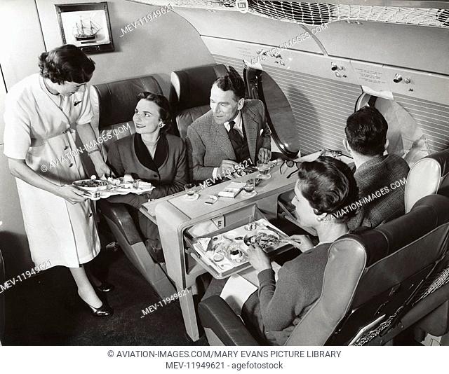 A Stewardess in the Bea Viscount Flagship Discovery Serving In-Flight Meals and Drinks to Passenger Sitting in a Club Seating Arrangement in the First-Class...