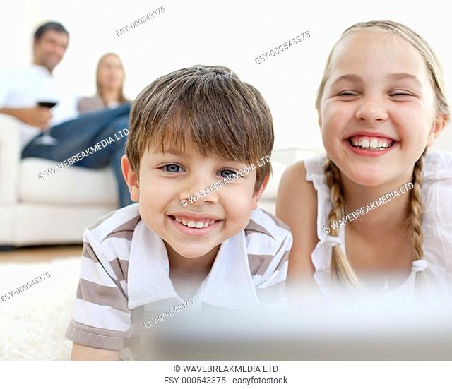 Cute siblings lying on the floor smiling at the camera