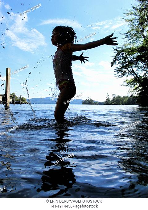 A young child splashing in a lake in New Hampshire