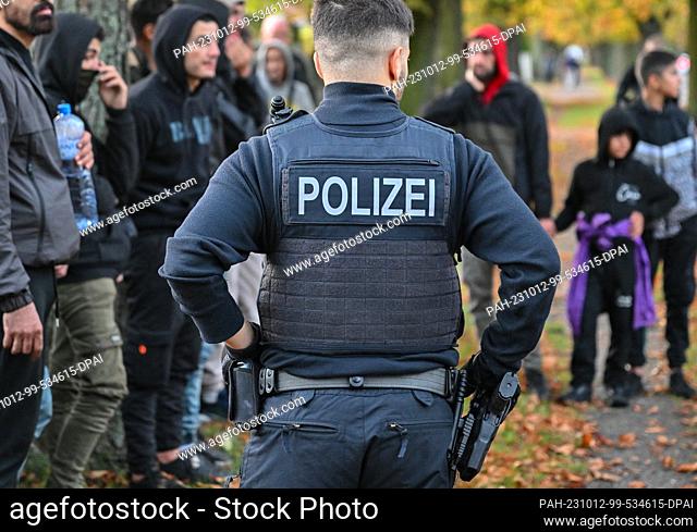 11 October 2023, Brandenburg, Forst: Illegal migrants are guarded by a federal police officer near the German-Polish border in Forst (Lausitz)