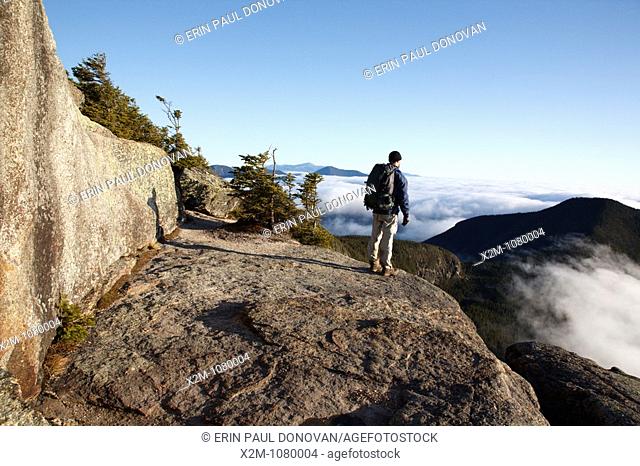 A hiker takes in the view of undercast from the summit of Mount Osceola in the White Mountains, New Hampshire USA