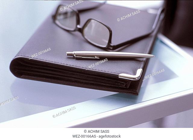 Ballpen and spectacles on briefcase