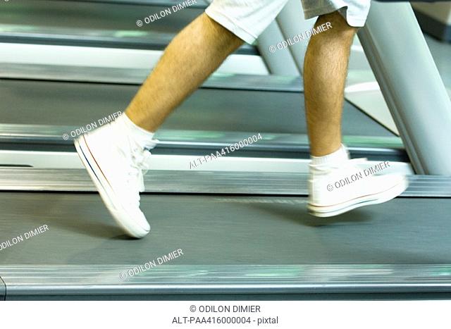 Man running on treadmill, knee down, blurred motion