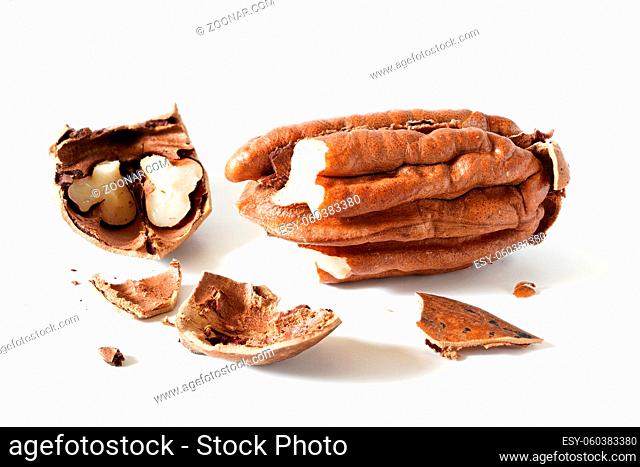 Pecan nut - Carya illinoinensis - cracked open, shells on table, isolated on white background, detailed closeup photo