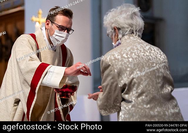 30 May 2020, Bavaria, Munich: Josef Schmid, a candidate priest, hands over a host during a service in the Liebfrauendom after his ordination as a deacon