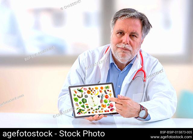 Doctor nutritionist holdingb digital tablet.with vegetable and fruit on screen