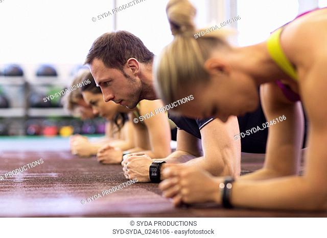 man at group training doing plank exercise in gym