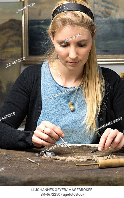 Restoration studio, restorer, woman restores lent scarf with tools on worktable in Atelier, Munich, Bavaria, Germany