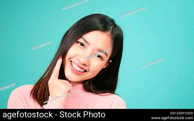 Portrait young Asian beautiful woman smiling wear silicone orthodontic retainers on teeth isolated on blue background, Teeth retaining tools after removable...