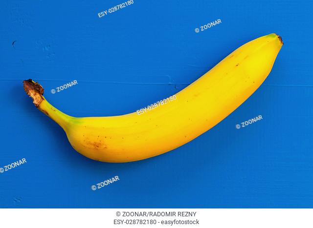 Single banana isolated on the blue table