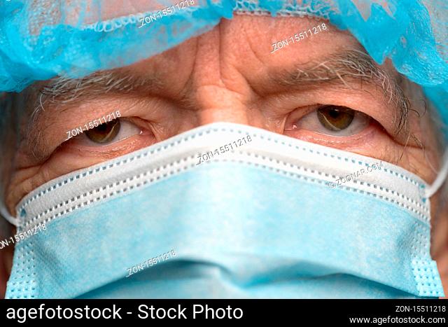 Close up portrait of sad senior adult dressed in surgical face mask with ear straps, covering nose from SARS, virulently infectious disease corona virus