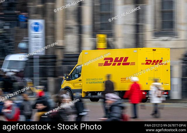 12 December 2023, Saxony, Dresden: An electric van from the DHL parcel and letter express service drives across Theaterplatz in the old town in the morning