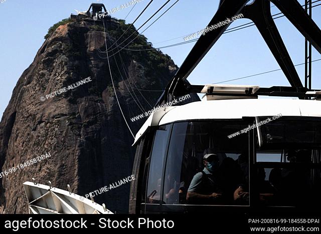 15 August 2020, Brazil, Rio de Janeiro: People with mouthguards are sitting inside the Bondinho, the cable car at Sugar Loaf Mountain