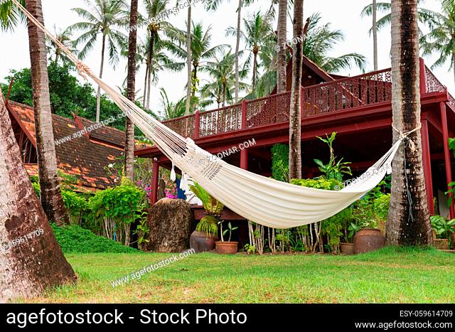 Hammock hung on palm trees near a wooden hotel for relax vacation