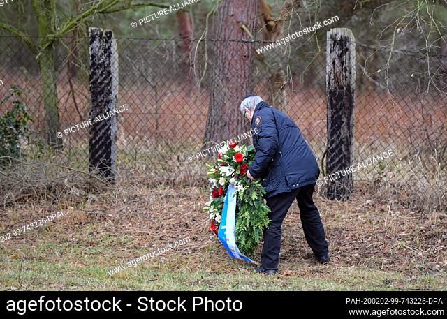 02 February 2020, Brandenburg, Jamlitz: Peter Fischer of the Central Council of Jews in Germany lays a wreath of flowers on the fence of the former camp at the...