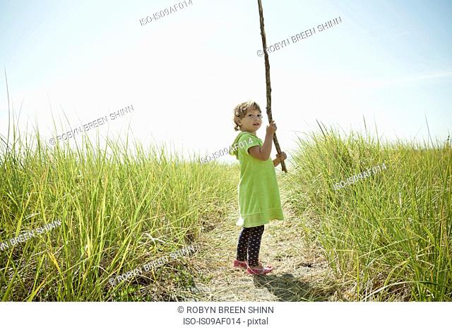 Portrait of female toddler holding long stick