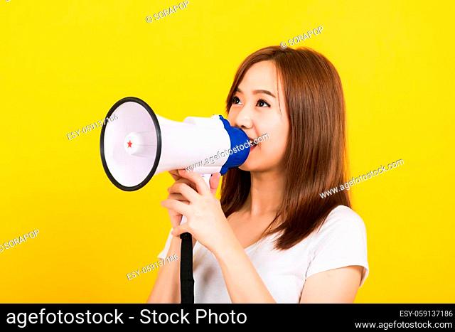 Asian happy portrait beautiful cute young woman teen standing making announcement message shouting screaming in megaphone looking to side isolated