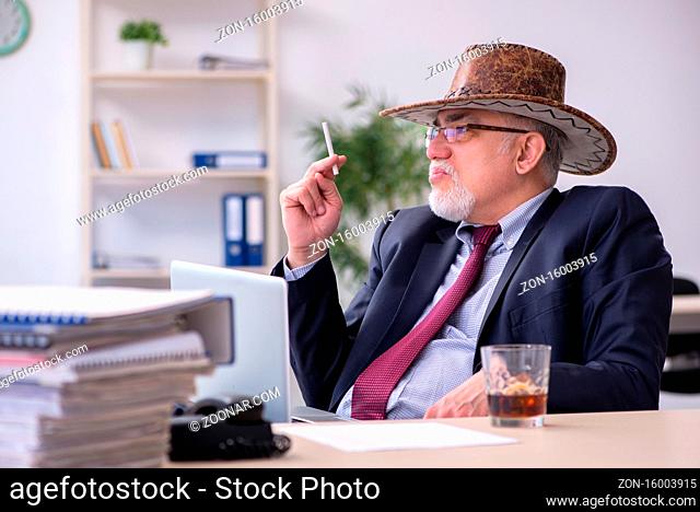 Funny old boss in cowboy hat in office