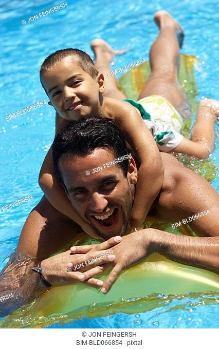 Father giving son piggyback ride in swimming pool