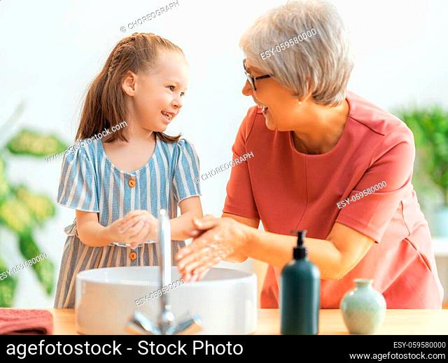 A cute little girl and her grandmother are washing their hands. Protection against infections and viruses