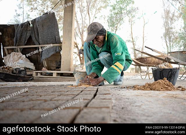 28 February 2023, Tunisia, Nefta: A brickmaker shapes a clay mixture into adobe bricks using a wooden frame. Photo: Sebastian Kahnert/dpa