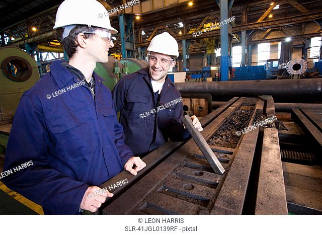 Workers examining metal in steel forge