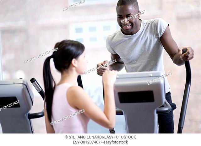 Two young people speaking while exercising at gym