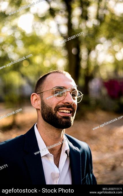 Happy businessman wearing eyeglasses in park