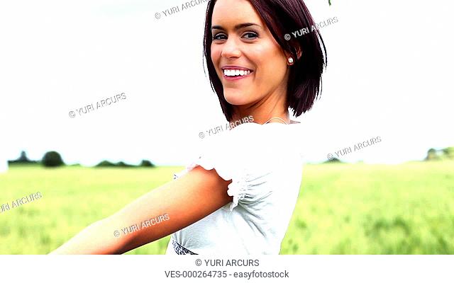 Cute young woman smiling and laughing while holding some wheat and twirling around