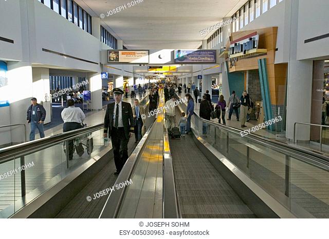 Travelers and airline industry personnel on moving sidewalks in Newark International Airport, New Jersey