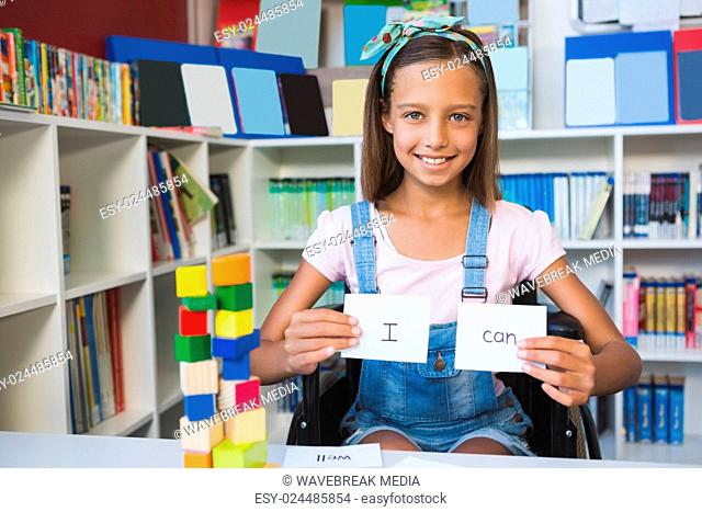Disabled girl showing placard that reads I Can in library