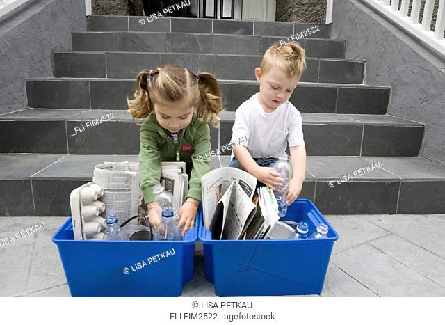 Children placing items in recycling box, British Columbia