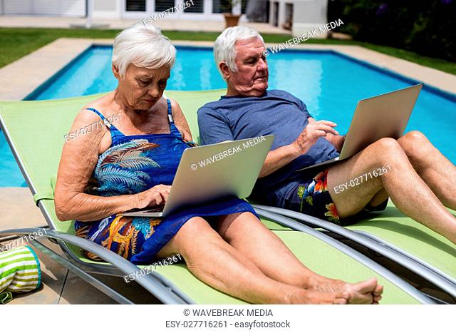 Senior couple using laptop on lounge chair