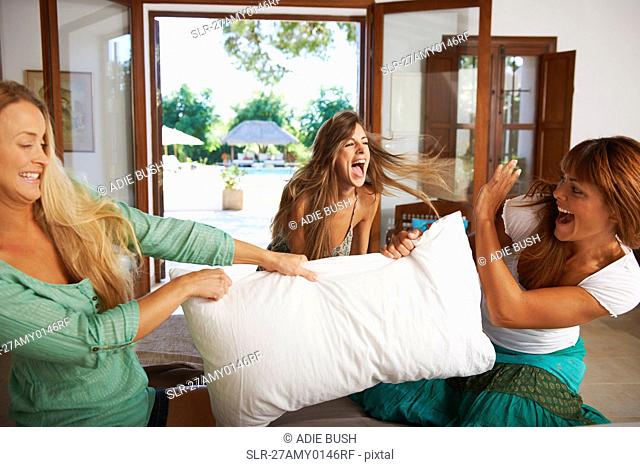 Women having pillow fight on hotel bed